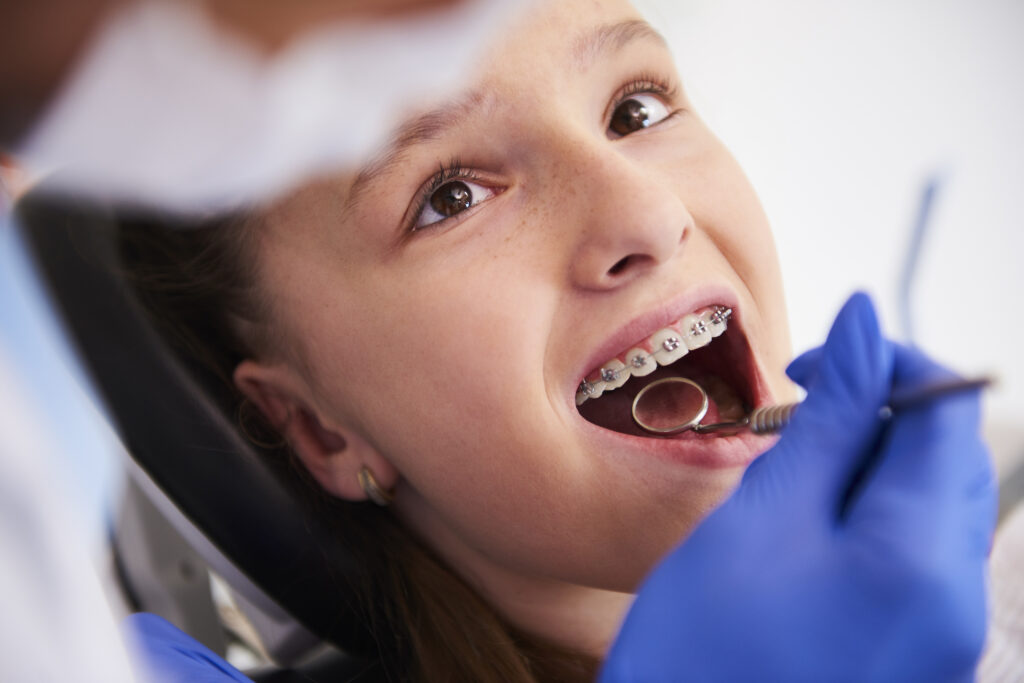 Orthodontist adjusting metal braces for kids in Buffalo, NY.